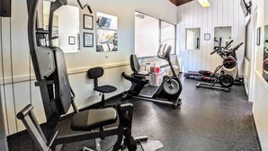 Ein Fitnessstudio mit verschiedenen Trainingsgeräten, darunter Laufband, Ergometer und Kraftgeräte.