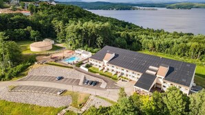 Et hotel med stor parkeringsplads, swimmingpool og udsigt til sø og bjerge.