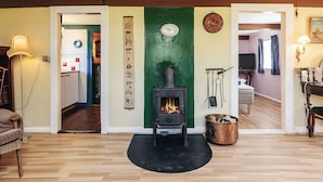 Ein gemütliches Wohnzimmer mit Kaminofen, Kamin und Essbereich mit Tisch und Stühlen.
