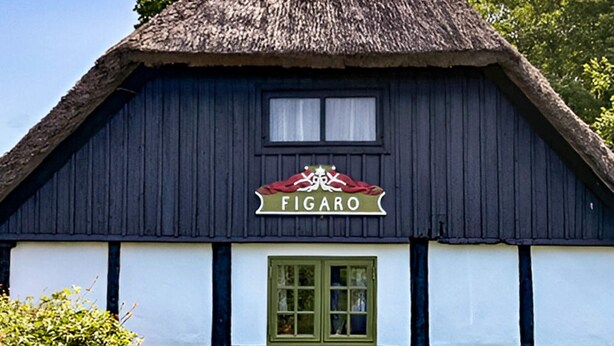 Ein traditionelles Gebäude mit einem Strohdach und einem Schild mit der Aufschrift „FIGARO“.