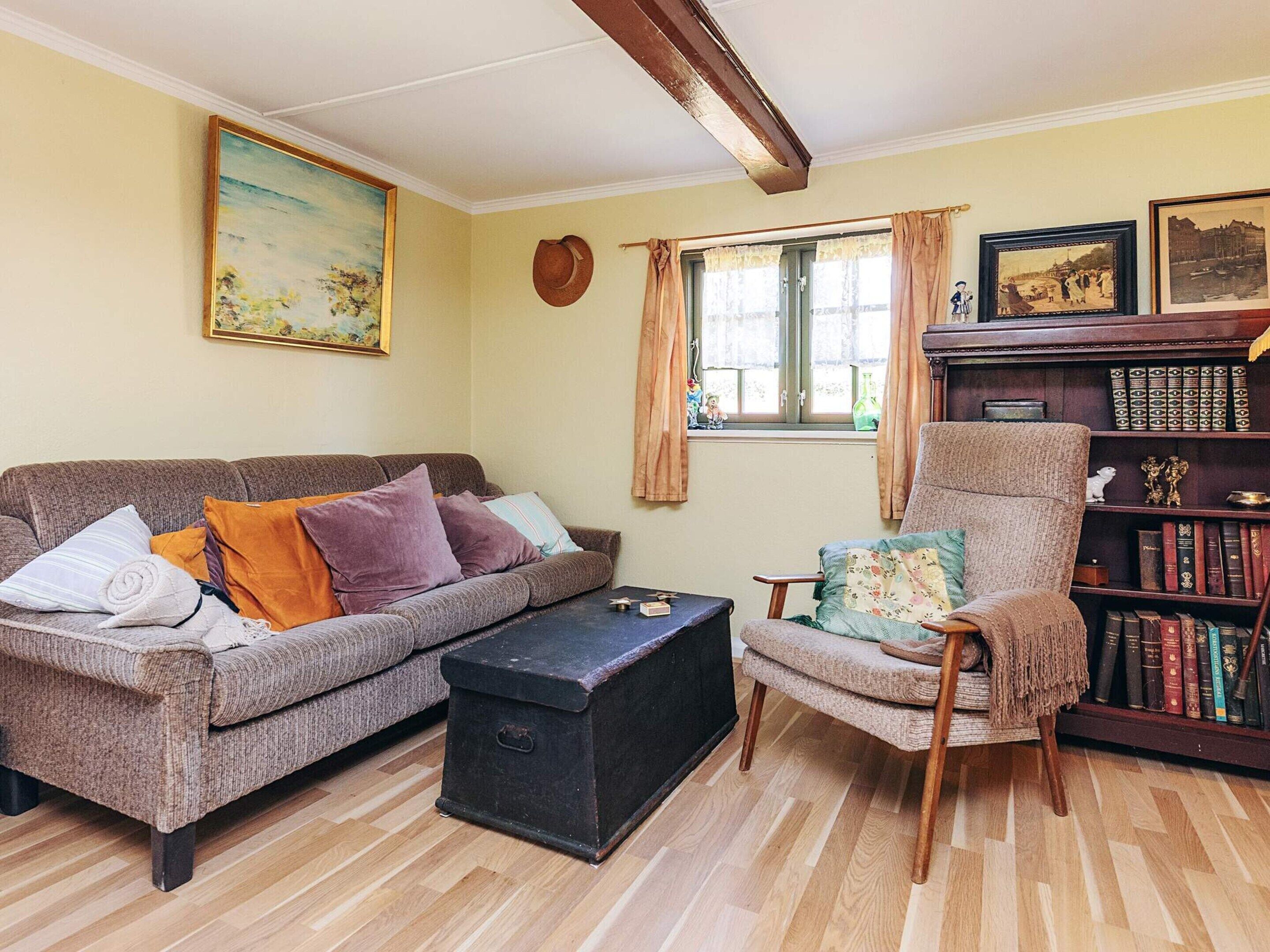 Una sala de estar acogedora con un sofá, un sillón y una estantería llena de libros.