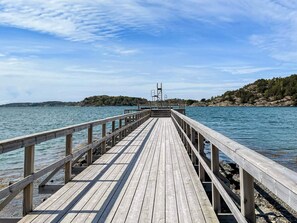 A wooden pier extending into calm water, with a rocky shoreline and trees in the background. - 4 Star Holiday Home in Myggenas (Myggenäs)