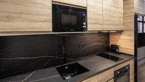 A modern kitchen with a black microwave, a built-in oven, and a sleek black countertop.