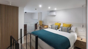 A modern bedroom with a bed, bedside tables, a desk, and a chair.
