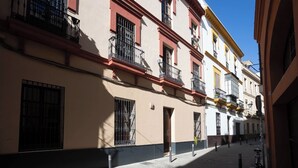 A narrow cobblestone street lined with multi-story buildings featuring balconies and barred windows.