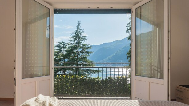 Ein Schlafzimmer mit einem großen Fenster und Blick auf einen Berg und einen See.