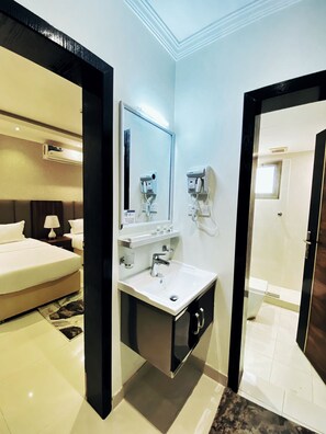 Une salle de bain d’hôtel moderne, dotée d ’un grand miroir, d’un lavabo et d’un sèche-cheveux.