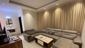 Ein modernes Wohnzimmer mit einer Eckcouch, einem Couchtisch und einem Essbereich mit kleinem Tisch und Stühlen.