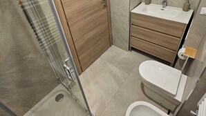 A modern bathroom with a glass shower enclosure, a wooden door, a sink with a mirror, and a toilet. - B&B Lunis (Trieste)