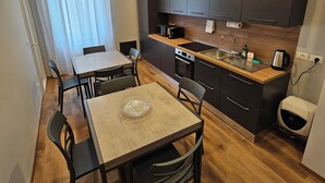 A modern kitchen with dark cabinets, a wooden countertop, and a dining area with a table and chairs. - B&B Lunis (Trieste)