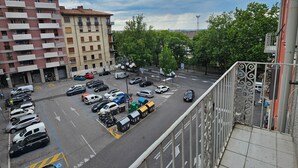 A parking lot with multiple cars and a few delivery trucks. There are buildings with balconies and a clear sky with some clouds. - B&B Lunis (Trieste)