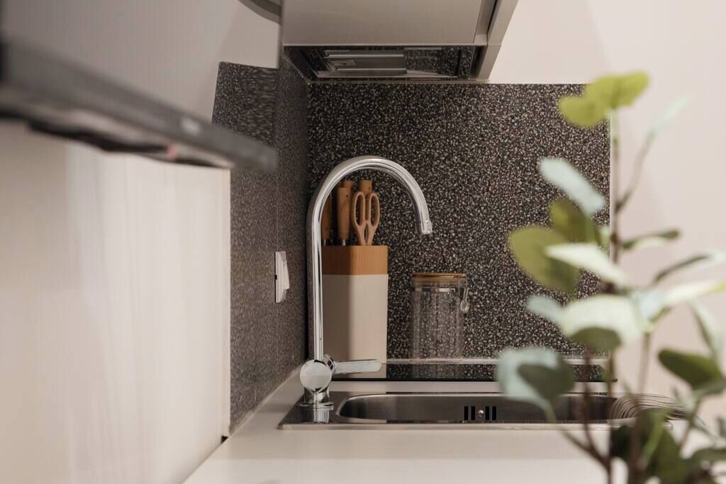 Eine moderne Küche mit Granit-Spritzschutz, Edelstahl-Spüle und Dunstabzugshaube.