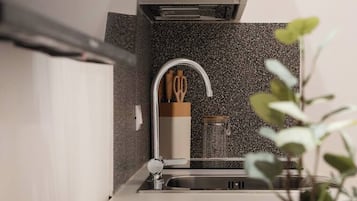 Eine moderne Küche mit Granit-Spritzschutz, Edelstahl-Spüle und Dunstabzugshaube.