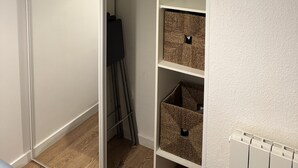 A walk-in closet with a sliding door, a black hanger, and wicker baskets on shelves.