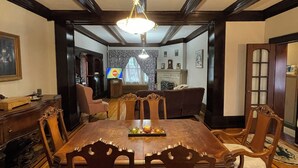 Une salle à manger élégante, avec une grande table en bois, des chaises richement décorées et un lustre.