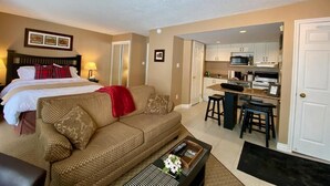 A hotel room with a bed, a sofa, a coffee table, and a kitchenette area. - Quiet Hillside Studio (Blue Mountain)