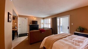 A hotel room with a bed, a desk, a chair, a sofa, and a television. - Quiet Hillside Studio (Blue Mountain)