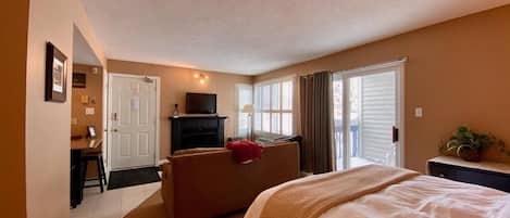 A hotel room with a bed, a desk, a chair, a sofa, and a television.