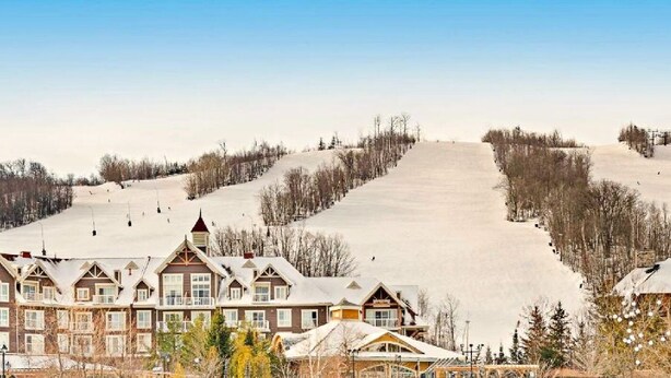 A ski resort with multiple buildings, a ski slope, and a clear sky. - Quiet Hillside Studio (Blue Mountain)