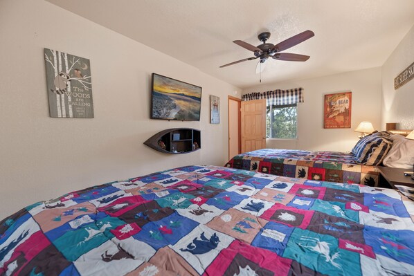 A bedroom with two beds, a ceiling fan, and various wall decorations including a poster and a framed picture. - Chalet Colusa (Big Bear Lake)