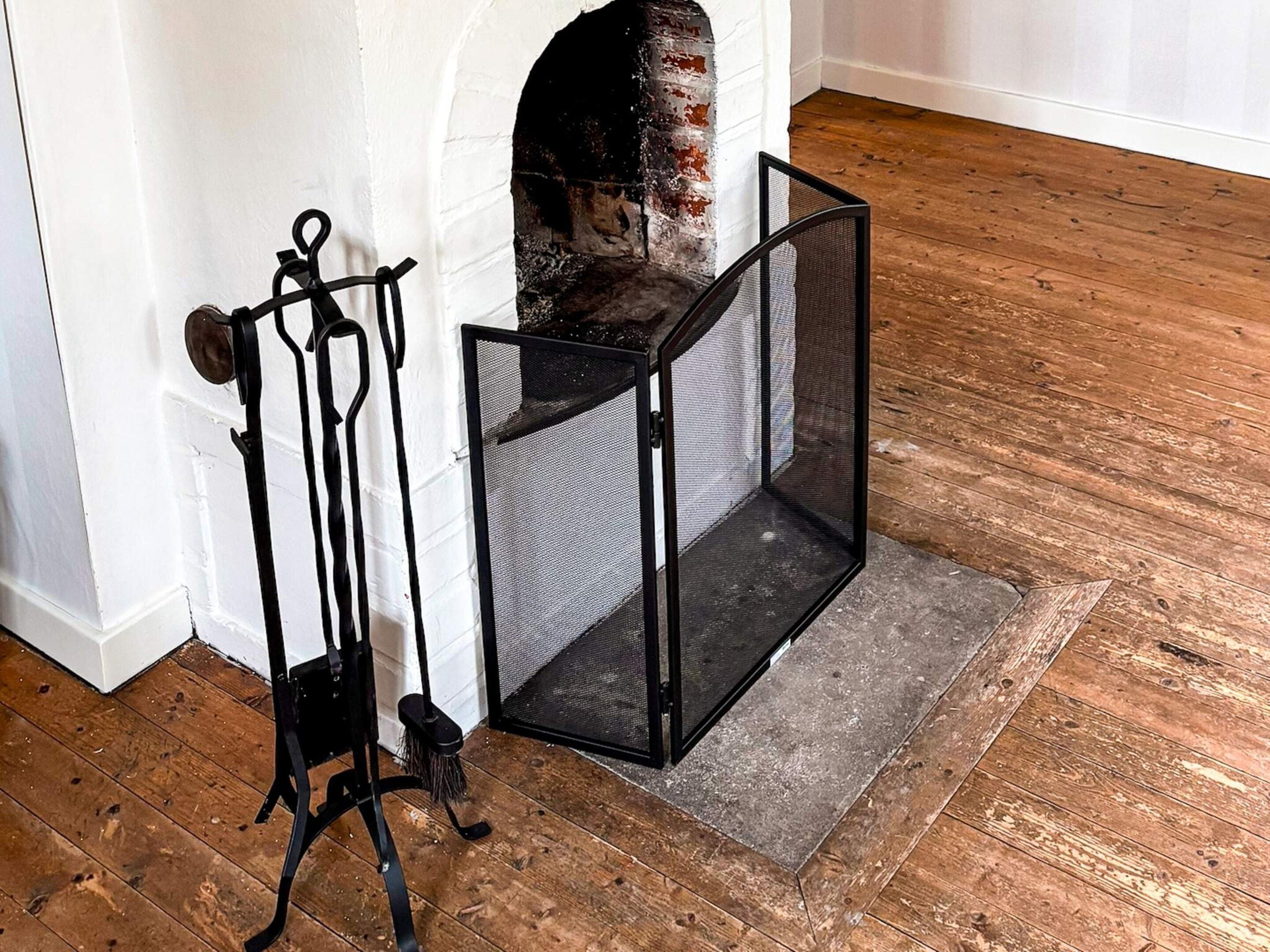 Una esquina de una habitación con una pared blanca, una chimenea de ladrillo y una puerta mosquitera de metal negro.