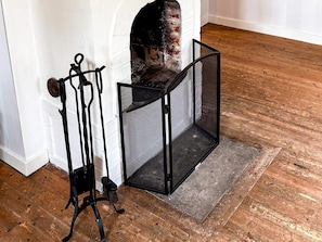 A corner of a room with a white wall, a brick fireplace, and a black metal screen door. - 5 Person Holiday Home in Aryd (Åryd)