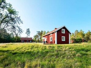 A red house with a sloped roof, a front porch, and a small attached garage. - 5 Person Holiday Home in Aryd (Åryd)