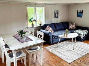 A living room with a dining table, white chairs, a blue sofa, and a small white table. - 5 Person Holiday Home in Aryd (Åryd)