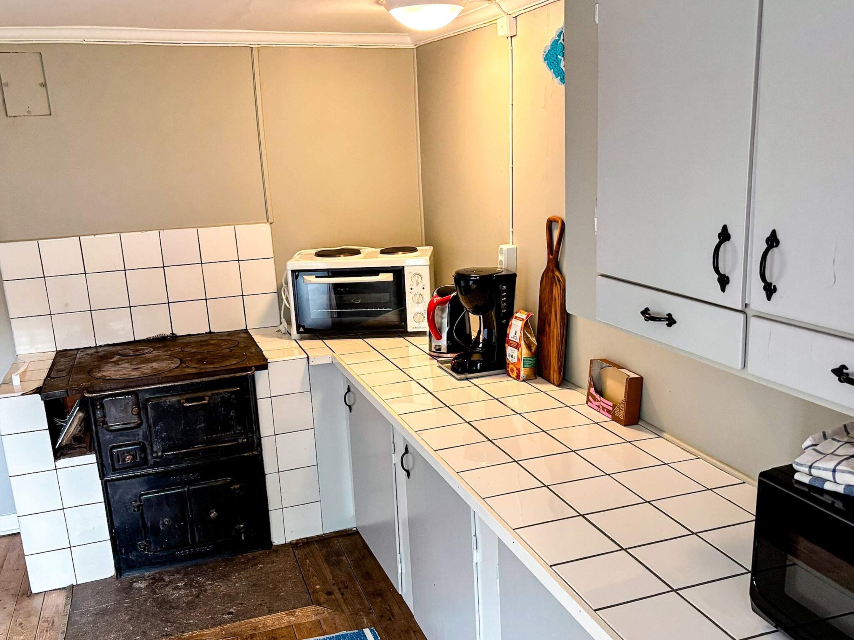A kitchen with a stove, a toaster, a coffee maker, and cabinets.