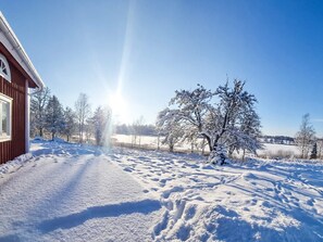 A snow-covered landscape with a building on the left and trees in the background. - 5 Person Holiday Home in Aryd (Åryd)