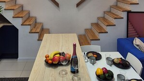 A modern kitchen with a wooden table set for a meal, a staircase, and a hanging light fixture.