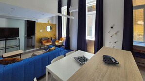 A modern living room with a sofa, chairs, a table, and a TV.