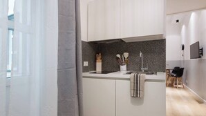 A modern kitchen with white cabinets, a granite countertop, and a stainless steel sink. - Stylish Gem in Historic Trieste  (Trieste)