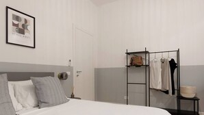 A hotel room with a bed, a wardrobe, a clothing rack, and a framed picture on the wall. - Stylish Gem in Historic Trieste  (Trieste)