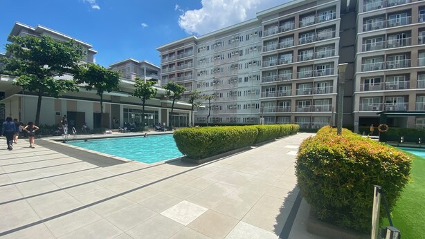 Un immeuble d’appartements moderne doté d’une piscine, d’un espace extérieur aménagé et d’un jardin bien entretenu.