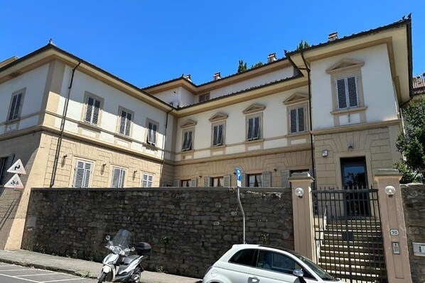 A two-story building with a stone wall and a gated entrance.