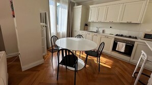 A compact kitchen with white cabinets, a round dining table with four chairs, and a visible oven. - Historic house with garden across from NYU Florence (Unknown)