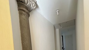A hallway with a marble floor, a fire extinguisher, and a door at the end. - Historic house with garden across from NYU Florence (Unknown)