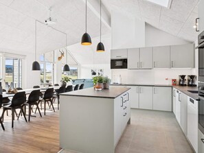 A modern kitchen with white cabinetry, a central island, and pendant lighting.