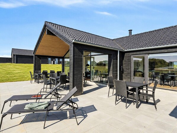 An outdoor patio area with tables and chairs, a covered seating area, and a view of the surrounding landscape.