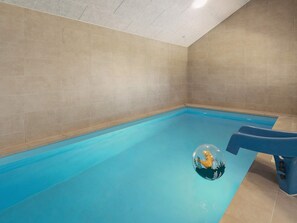 A swimming pool with a blue ball and a blue chair.