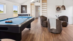 A pool table with balls, a sofa, and a lamp in a room with wooden floors and white walls. - 5 Star Holiday Home in Bogense (Bogense)