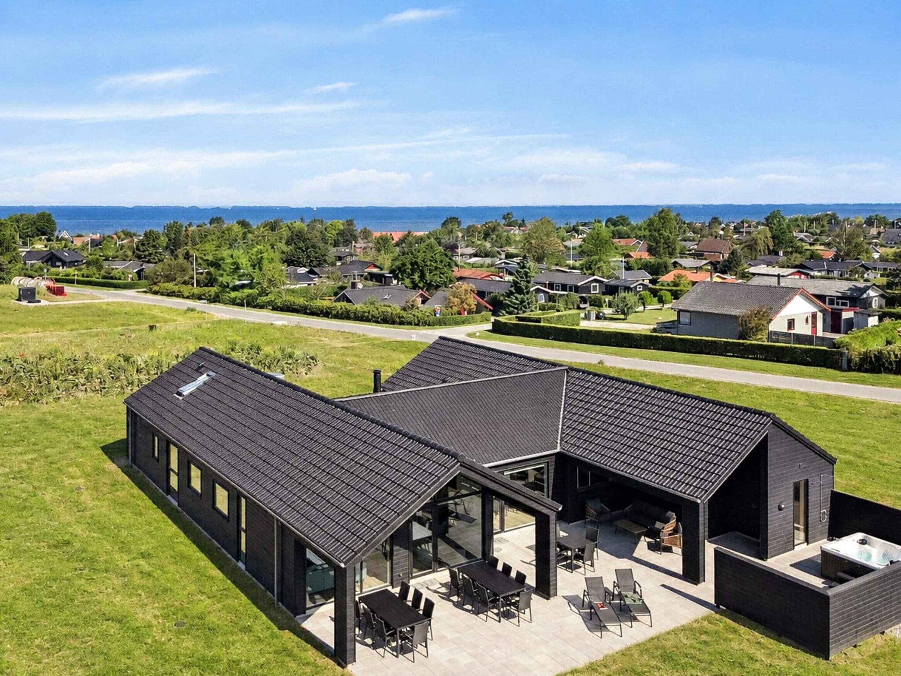 A modern house with a large patio area, a swimming pool, and a view of a residential neighborhood.