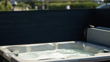 A hot tub with a glass of water on the edge, surrounded by a dark fence.