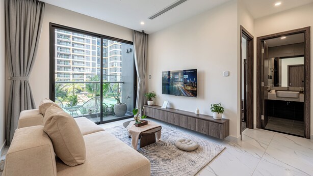 A modern living room with a sofa, a coffee table, a TV, and a large window with curtains.