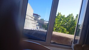 A room with a large window overlooking a street with buildings and trees. - Guest House An & Tea House (Bukhara)