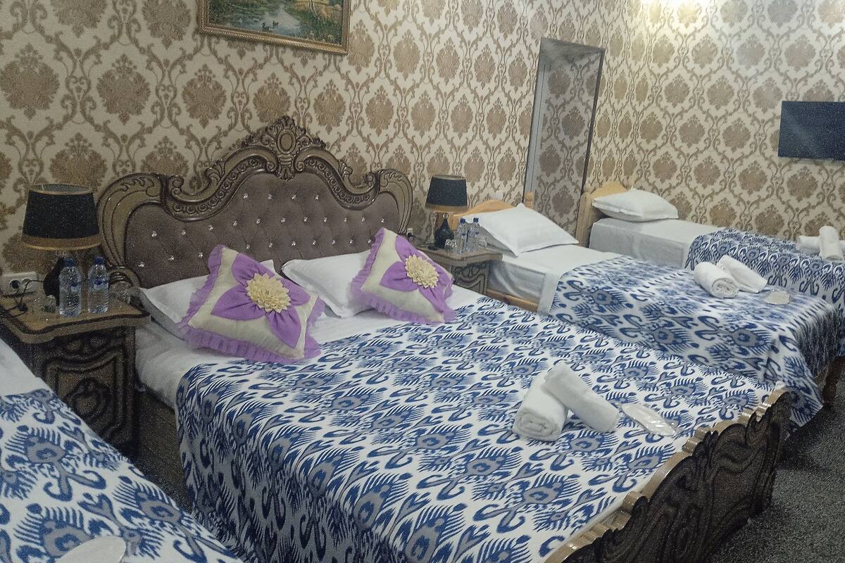 A hotel room with a large bed, two bedside tables, a nightstand, a mirror, and a painting on the wall.