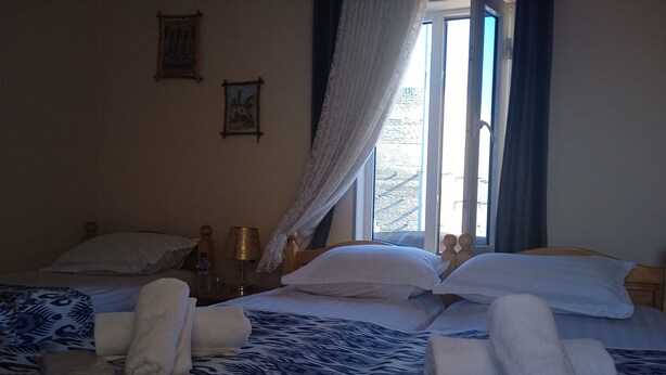A hotel room with a bed, a nightstand, a lamp, and a window with curtains. - Guest House An & Tea House (Bukhara)