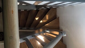 A wooden staircase with a metal handrail and a skylight above.