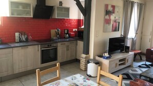 A kitchen with a red brick backsplash, wooden cabinets, a built-in oven, and a dining area with a floral tablecloth.